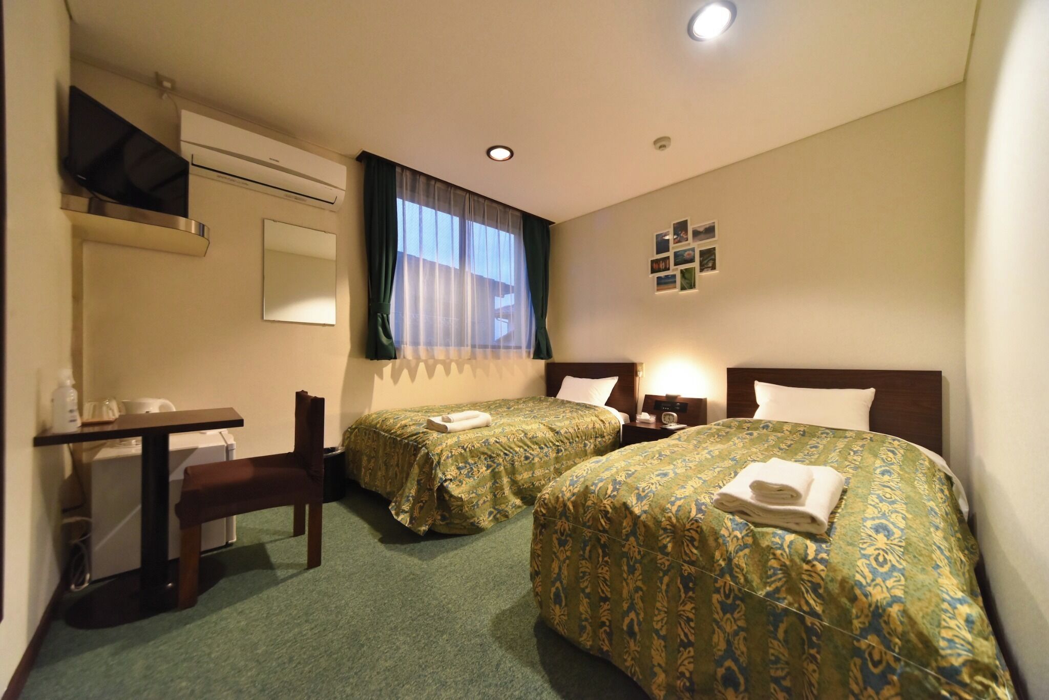 Een hotelkamer met twee bedden, een bureau, een stoel, een televisie en een raam met gordijnen.