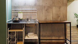 A compact kitchen with a sink, a small countertop, and a wooden table. - Hotel Nomad Hitachi (Hitachi)