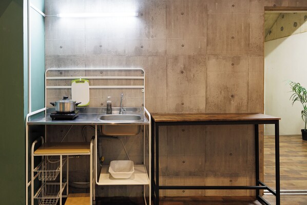 Una cocina compacta con un lavamanos, una pequeña encimera y una mesa de madera.