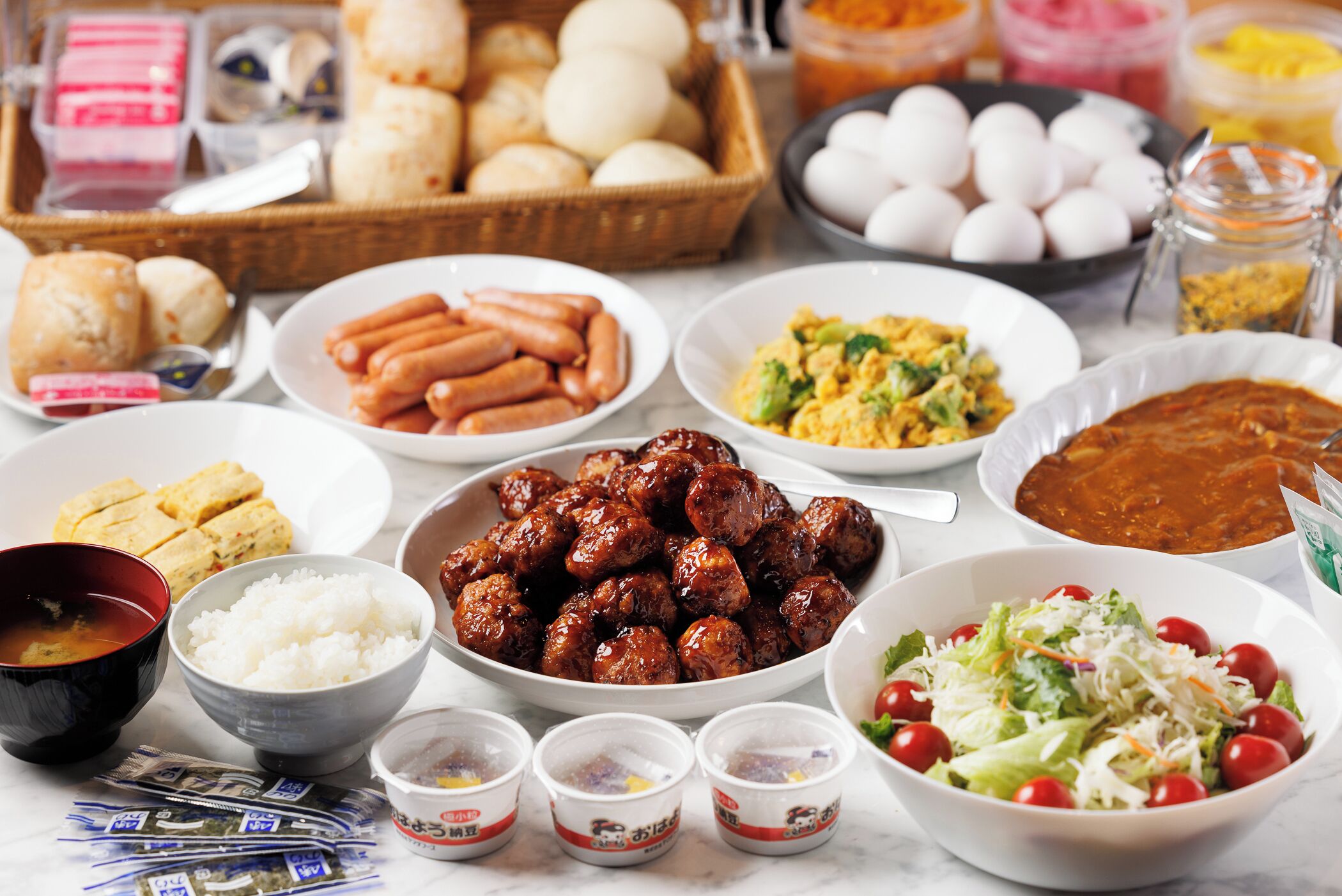 Uma mesa com diversos pratos, incluindo salsichas, arroz e salada.