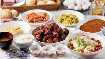 Uma mesa com diversos pratos, incluindo salsichas, arroz e salada.