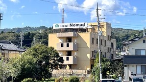 A hotel named 'Hotel Nomad' with a modern design, located in a residential area with hills in the background. - Hotel Nomad Hitachi (Hitachi)