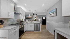 A modern kitchen with white cabinetry, a central island, and a stainless steel dishwasher.