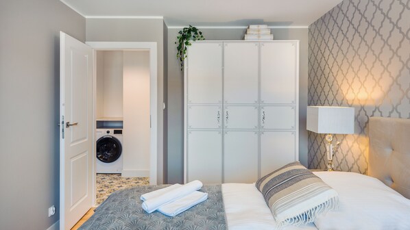 A hotel room with a bed, a wardrobe, a washing machine, and a lamp. - Sun & Snow Leśna (Hel)
