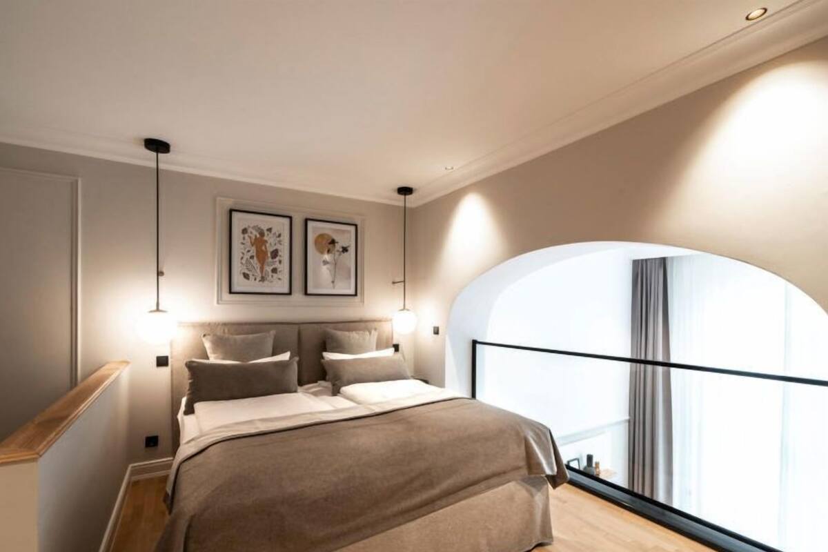 Un dormitorio moderno con una cama grande, suelo de madera y un amplio ventanal con vistas.