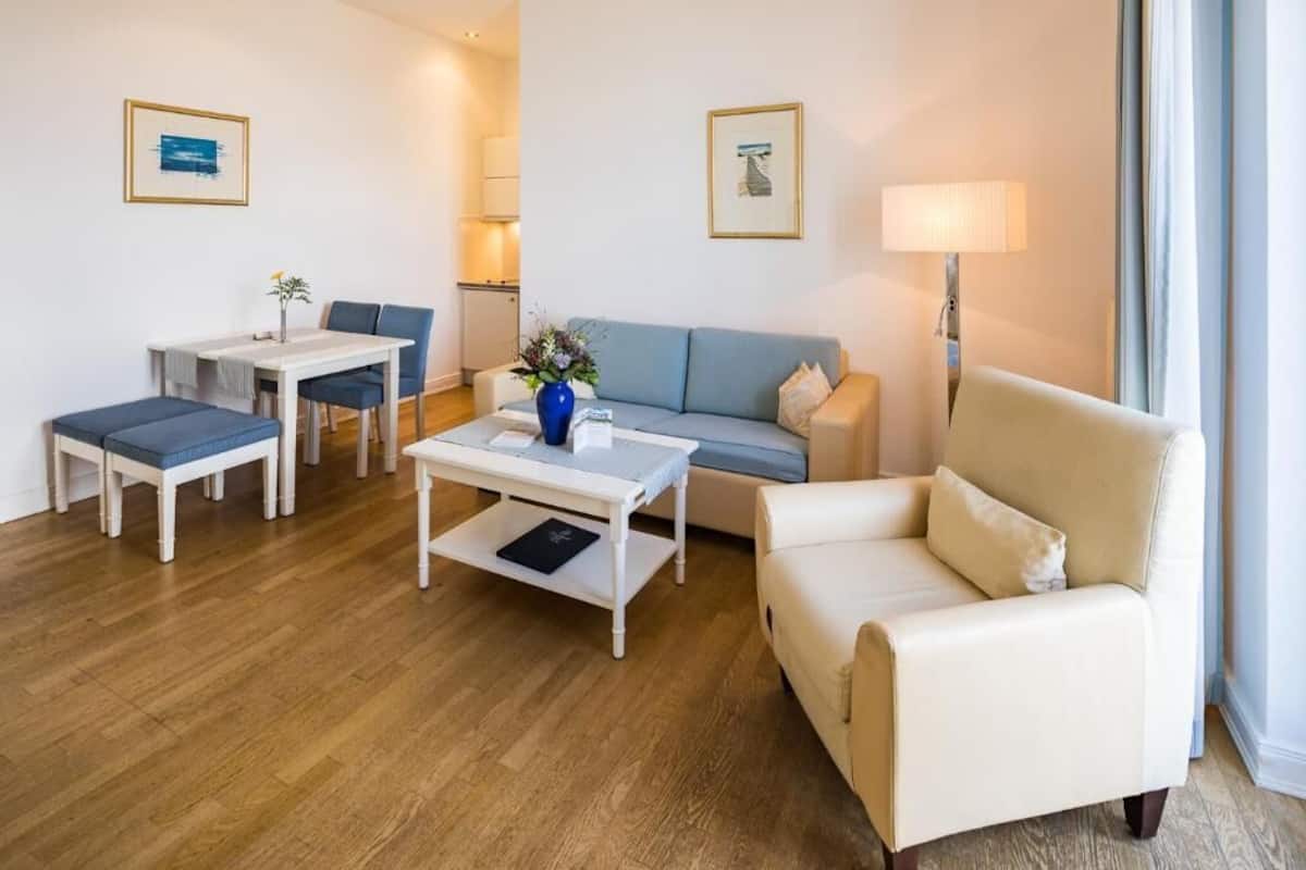 Una sala de estar moderna con un sofá, dos sillones, una mesa de centro y una mesa de comedor.