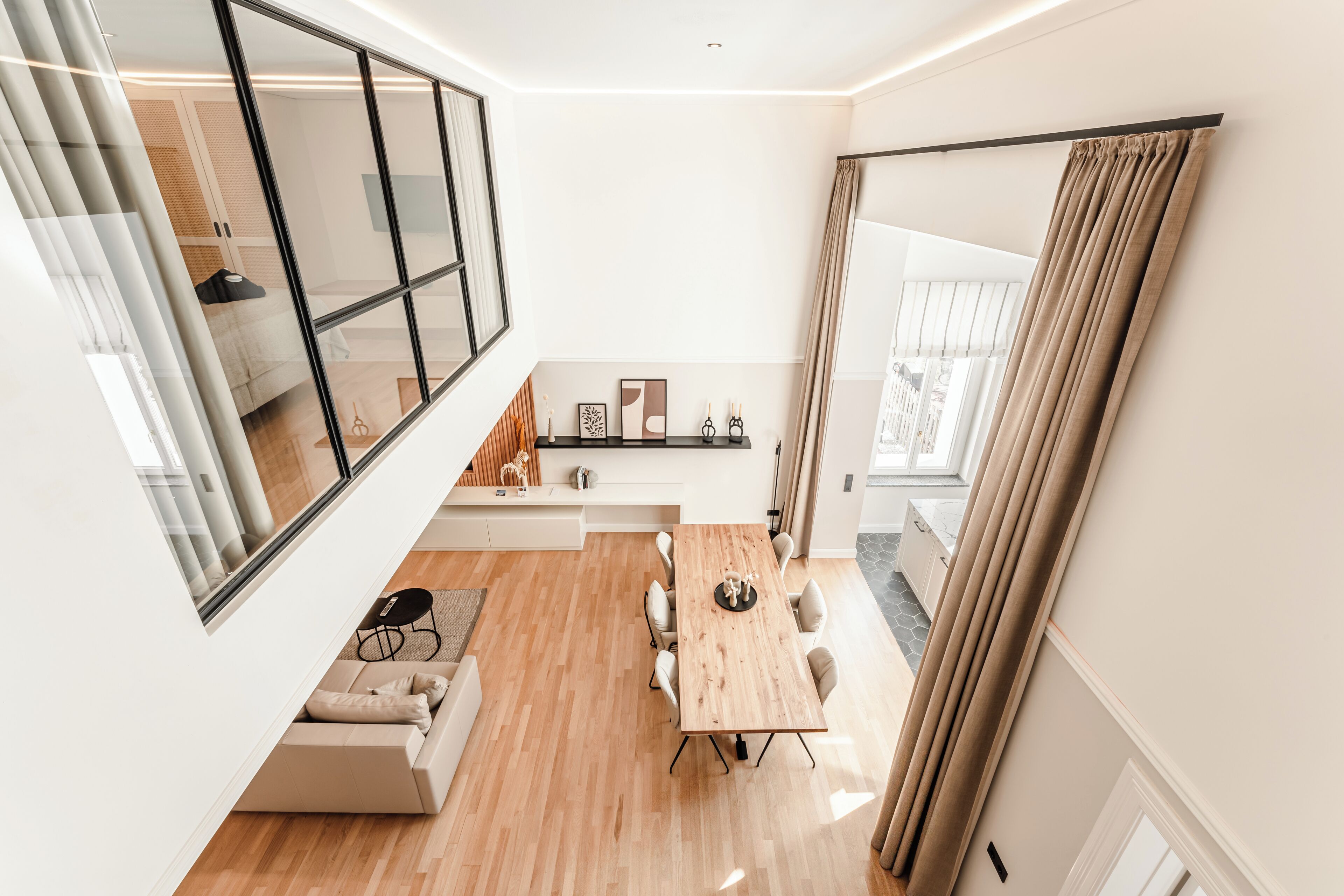 A modern living space with a dining area, a sofa, a small table, and a large window.
