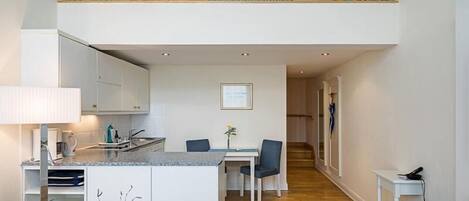 Un apartamento moderno con cocina, comedor y balcón con barandilla.