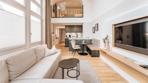 Una sala de estar moderna con un sofá, una mesa de centro, un televisor y una cocina al fondo.