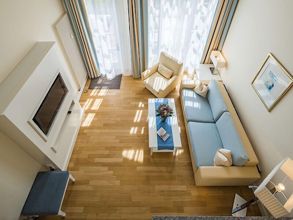 A modern living room with a sofa, armchairs, a coffee table, and a TV. - Strandhotel Kurhaus Juist (Juist)