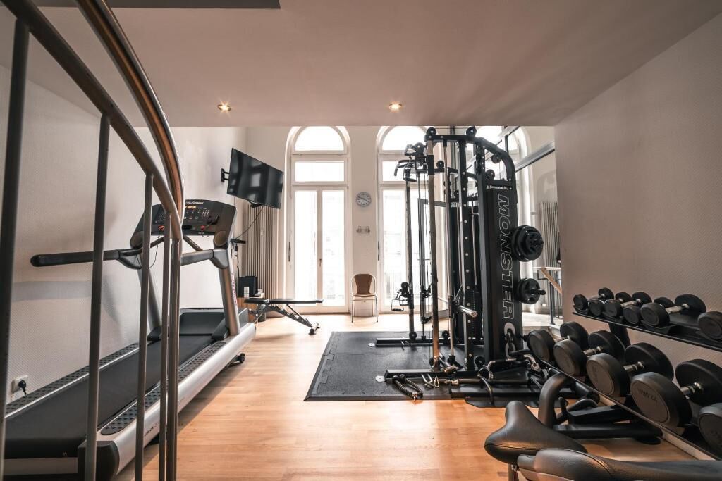 A gym with treadmills, weight machines, and dumbbells.