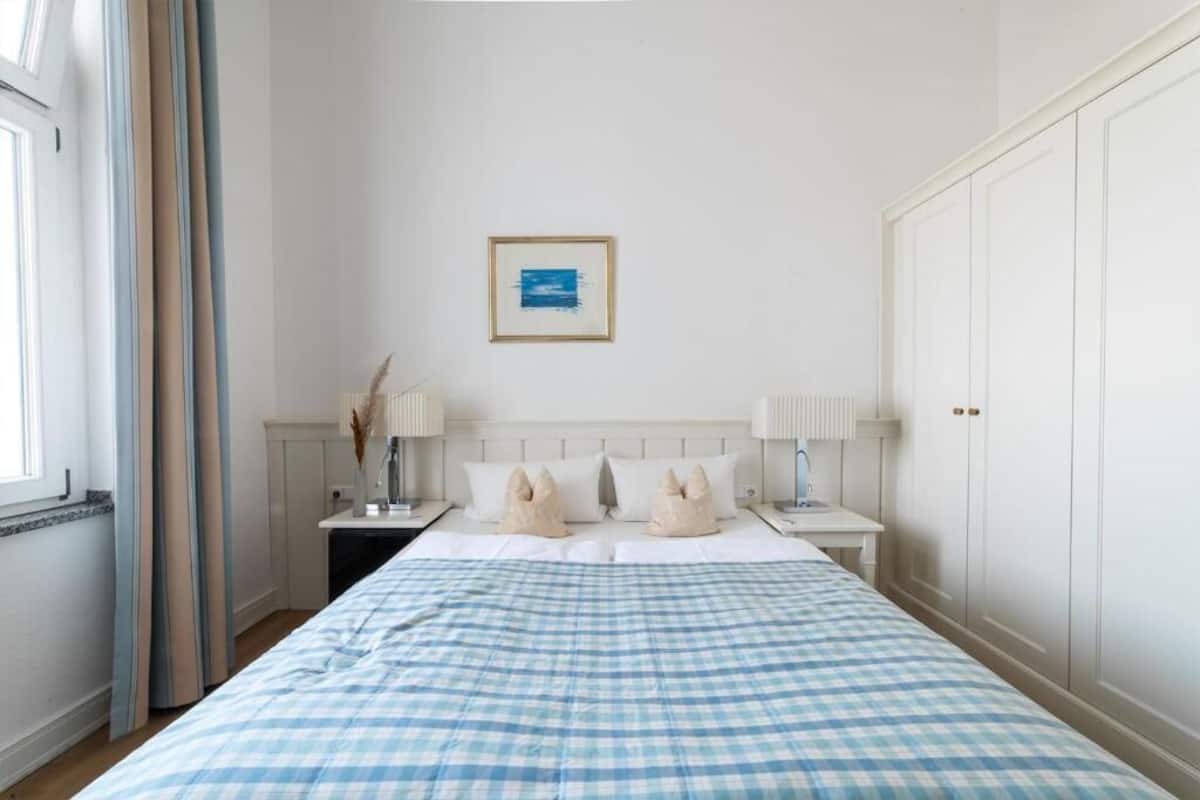Un dormitorio con una cama grande, dos mesitas de noche, un armario y un cuadro enmarcado en la pared.
