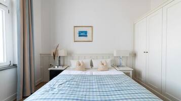 Ein Schlafzimmer mit einem großen Bett, zwei Nachttischen, einem Schminktisch und einem gerahmten Bild an der Wand.