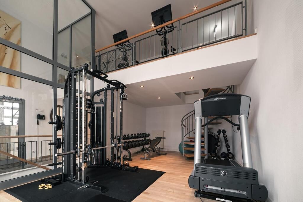 A gym with weightlifting equipment, a treadmill, and a staircase.