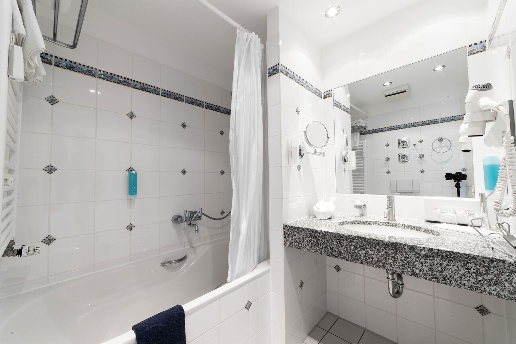 A modern bathroom with a bathtub, shower, and a large mirror.