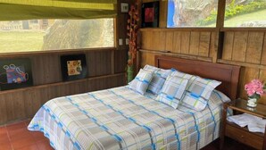 Une pièce en bois avec un lit, une table de chevet et une fenêtre donnant sur l’extérieur.