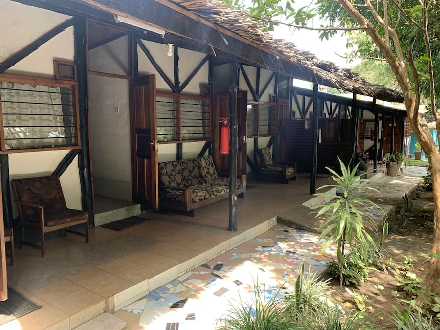 A covered outdoor seating area with wooden furniture and a tiled floor.