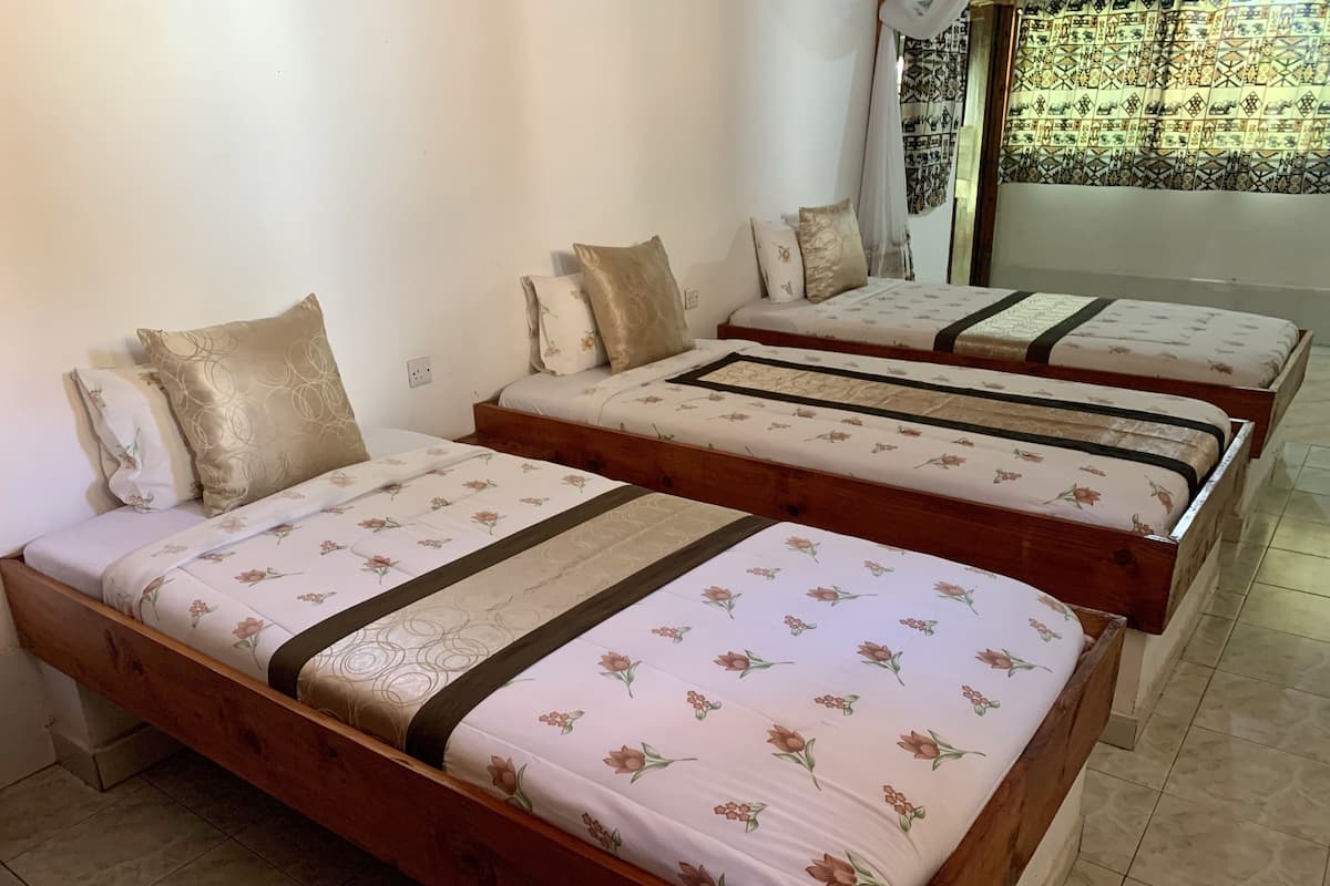 Una habitación con tres camas de madera, cada una con ropa de cama y almohadas a juego con motivos florales.