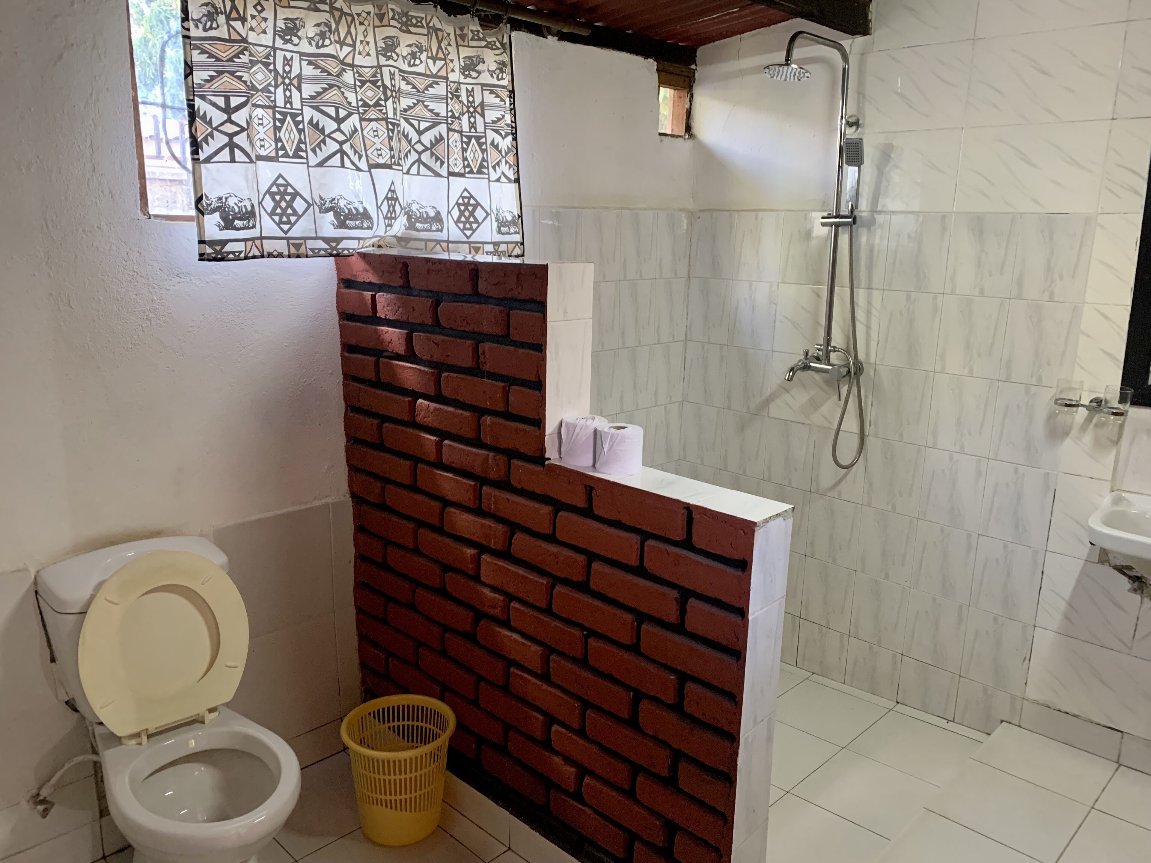 A bathroom with a toilet, a shower, and a sink.