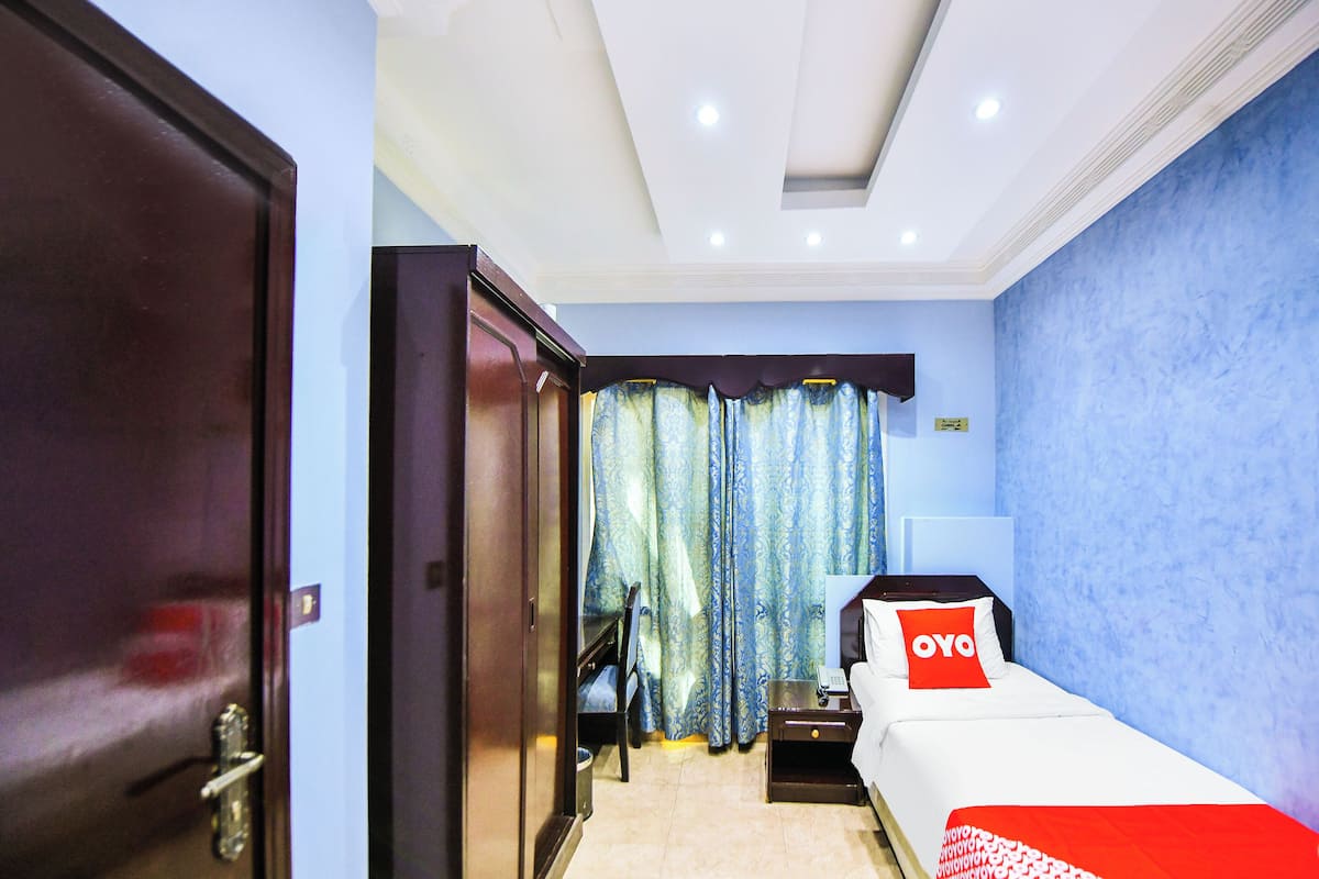 A hotel room with a bed, a desk, a chair, and a wardrobe.