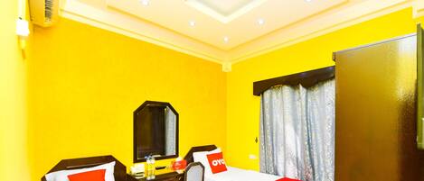 A hotel room with two beds, a desk, a mirror, and a wardrobe.