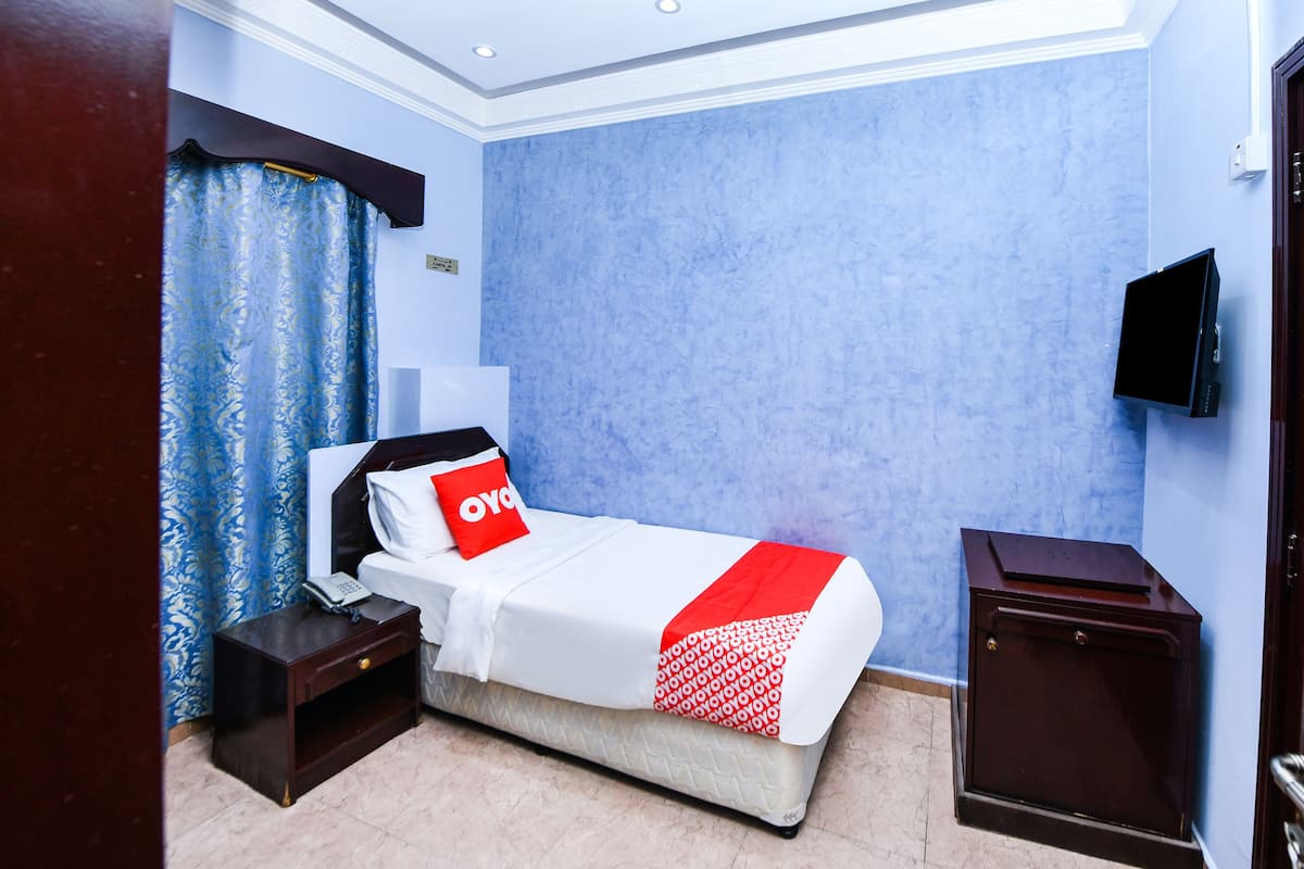 A hotel room with a bed, a nightstand, a TV, and a wardrobe.