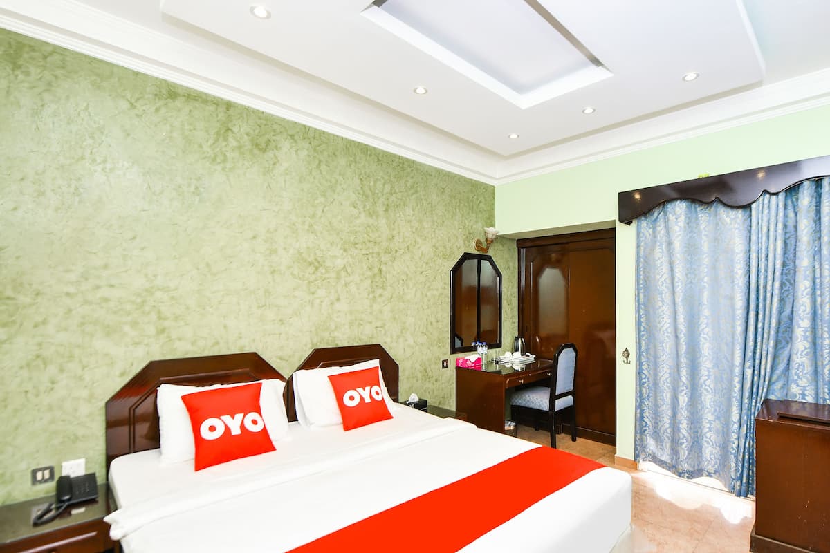 A hotel room with a bed, a desk, a chair, and a wardrobe.