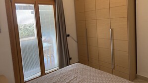 Una camera da letto con un letto, un armadio, una porta scorrevole con persiane e un condizionatore d'aria.