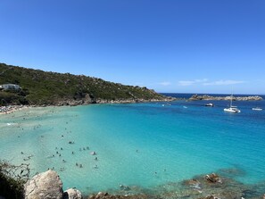 A coastal area with clear turquoise waters, rocky terrain, and boats.
