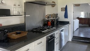 Una cocina moderna con armarios blancos, extractor de acero inoxidable y encimera negra.
