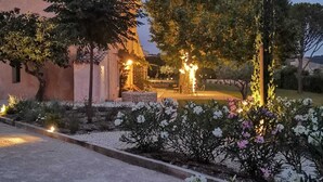 Un edificio con techo de tejas y un jardín con plantas y árboles en flor.