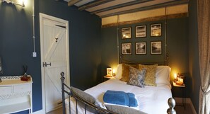 A bedroom with a bed, bedside tables, a wardrobe, and framed pictures on the wall. - Boutique Fisherman's Grade II Listed Cottage (Scarborough)