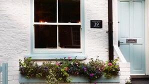 A building with a window, a door, and a sign indicating the address. - Boutique Fisherman's Grade II Listed Cottage (Scarborough)