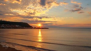 A sunset over a calm sea with a distant shoreline. - Boutique Fisherman's Grade II Listed Cottage (Scarborough)
