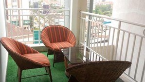 A balcony with wicker furniture and a glass table, overlooking a cityscape. - Stay.Plus Sandalwood Apartment Kilimani (Nairobi)