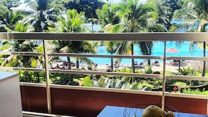 Un balcon donnant sur une piscine, entourée de palmiers et de verdure.