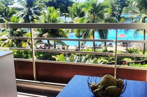 Un balcon donnant sur une piscine, entourée de palmiers et de verdure.