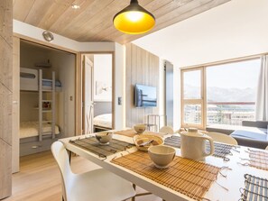Una habitación moderna con una litera, una mesa de comedor con individuales, cuencos y una tetera.