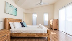 Un dormitorio amplio con una cama de madera, un ventilador de techo y un ventanal grande.
