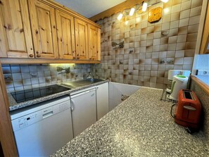 A kitchen with wooden cabinets, a dishwasher, a sink, and a toaster.