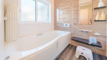 A modern bathroom with a bathtub, a shower, a toilet, a window, and a mirror.
