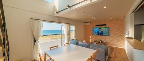 Un interno moderno con zona pranzo, posti a sedere, televisione e vista sul mare.