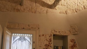 Een kamer met een structuurwand, een deur met een decoratief glasraam en een plank met een vaas.