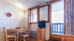 A cozy room with a wooden table, chairs, a television, and a balcony with a view. - Functional apartment in the center with balcony in La Plagne (La Plagne Montchavin Les Coches)