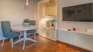 A modern kitchen with white cabinets, a built-in washing machine, and a dining area with a round table and chairs. - Ampio appartamento vicino al mare con una grande terrazza solarium. (Alassio)