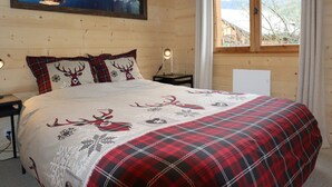 A cozy bedroom with a bed, a painting of a mountain, and a window with a view. - Spacious chalet near shops, pets allowed! (Samoëns)