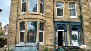 A corner building with a bay window, a door with a decorative arch, and a small balcony with a railing. - Charming 1-bed Apartment in Lytham Saint Annes (Lytham St. Anne's)