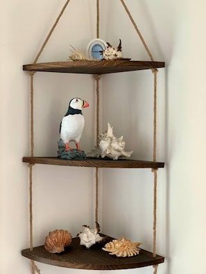 A corner shelf with a pufferfish figurine, seashells, and a small decorative item.