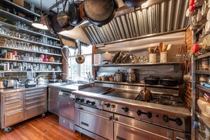 A commercial kitchen with stainless steel appliances, shelves with glassware, and various cooking utensils. - Beautiful home in Gan (Gan)