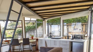 A modern kitchen with a wooden ceiling, a built-in stove, and a window overlooking greenery. - Cozy Loft with big terras having a spectaculair view of San Jose (San Antonio de Escazú)